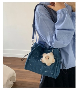 Detail of denim shoulder bag with white bow prints and a plush star pendant