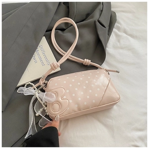 Detail of pink polka dot bag with decorative pearl charm and white mesh ribbon bow