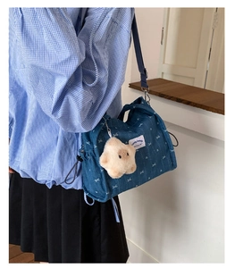 Detail of blue denim crossbody bag with white bow patterns and star plush charm