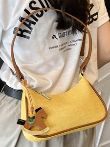 Chic yellow woven shoulder bag with brown strap and decorative rocking horse charm