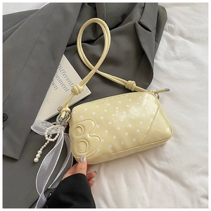Detail view of yellow polka dot baguette bag with pearl charm and silk ribbon bow