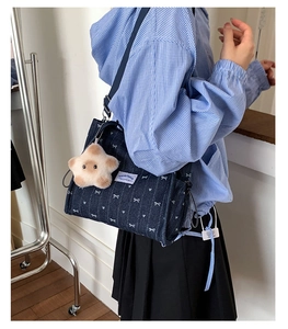Detail of dark blue denim crossbody bag with white bow patterns and plush star charm