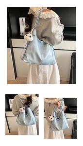 Detailed view of light blue tote bag with glossy leather finish and panda plush pendant