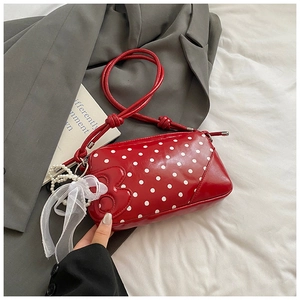 Close-up of red polka dot patent leather baguette bag with pearl mesh bow charm