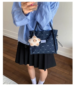 Close-up of navy denim tote bag with white bow patterns and plush star charm detail