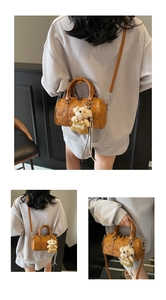 Detail of a brown cylindrical crossbody bag featuring a plush bear charm and vintage print