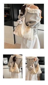 Detail of beige glossy tote bag with square stitching and a cute panda pendant