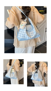 Detail view of light blue checkered backpack with plush bear charm and Luckygirl pattern