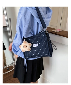 Detail of dark blue denim tote bag featuring white heart patterns and a plush star charm