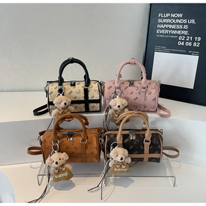 Detail of four colorful cylinder boston bags with bear patterns and plush bear charms