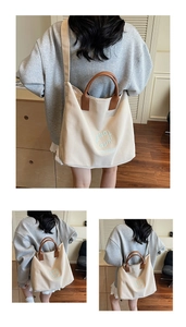 Detailed view of canvas tote bag showing cream body with brown handles and blue typography