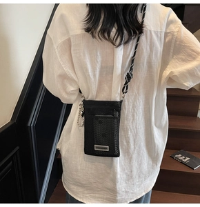 Detail of black nylon mesh crossbody phone bag with two-tone cord strap and metal hooks