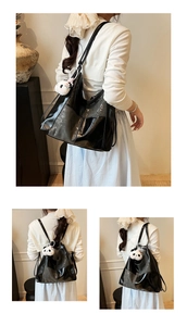 Detail of glossy black large tote bag with a cute white panda charm on casual shoulder strap