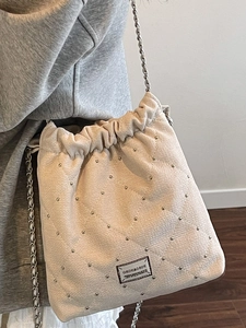 Chic cream quilted bucket bag with chain strap and silver rivets in 2025 fashion style