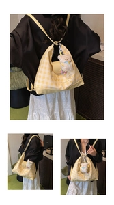 Detail of yellow checkered bag with plush bear charm and crossbody strap styling