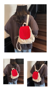 Detailed view of cream canvas backpack featuring a vibrant red flap and drawstring closure