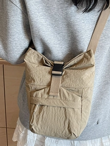 Sac bandoulière en nylon marron clair avec boucle porté par un mannequin en style décontracté