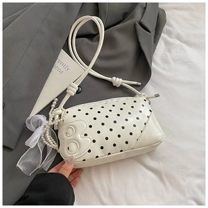 Detail of off-white polka dot baguette bag with pearl chain and lace bow accent