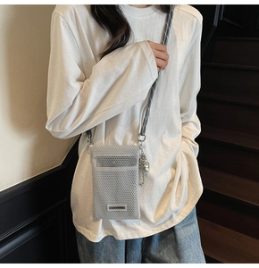 Close-up of light gray mesh phone bag with braided rope strap and branded cloth label