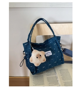 Close-up of blue denim tote bag featuring white heart patterns and a plush star charm