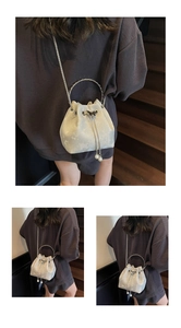 Close-up of luxury bucket bag with silver handles, pearl charms and metal bow detail