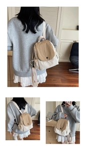 Detail view of khaki and cream canvas mini backpack with side drawstring pockets and button