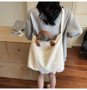 Detail of canvas tote bag with leather handles shown in a natural lifestyle setting