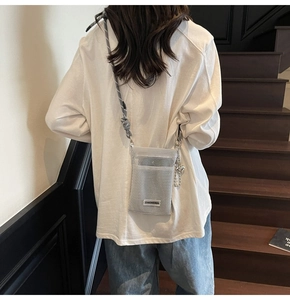 Detailed view of a white mesh crossbody phone bag with grey braided strap and silver bead