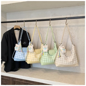 Detail of four colorful plaid crossbody bags with plush bear charms and heart embroidery