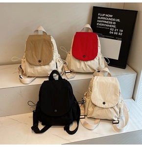 Detail view of canvas backpacks in four colors showing flap buckle and drawstring side pockets