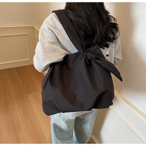 Detail view showing a large black tote bag with a unique knot shoulder strap design