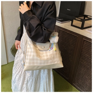Detail of cream checkerboard crossbody bag with Luckygirl embroidery and plush bear charm