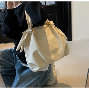 Detailed view of cream minimalist tote bag with unique shoulder strap knot design