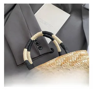 Detail of hand-woven straw bag featuring dual-tone thick handles and cartoon embroidery