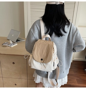 Detailed back view of a canvas backpack with khaki flap and drawstring side pockets