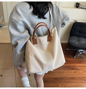 Detail of white canvas tote bag with brown leather straps and green embroidery art