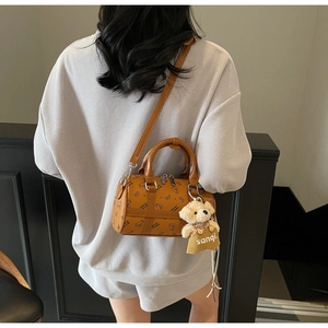 Brown cylinder shoulder bag featuring cartoon bear patterns and a plush teddy charm