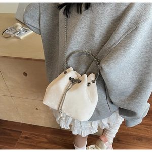 Detail of white velvet bucket bag with metal ring handle and pearl butterfly charm