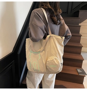 Detail of beige tote bag with neon cat graphic and detachable round coin purse hanging