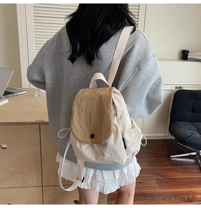Detail of canvas backpack featuring contrast flap closure and side drawstring pockets