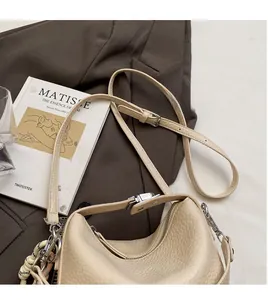 Detail of cream lychee leather handbag with adjustable long strap and woven rope charm