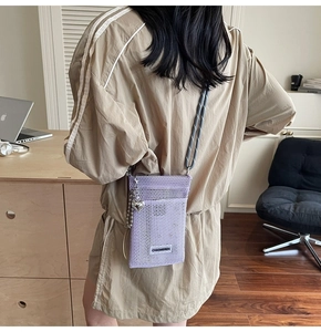 Detail of purple mesh crossbody phone bag with heart charm on khaki sweatshirt