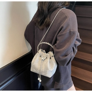 Detailed close-up of a grey satin bucket bag with pearl pendant and butterfly charm