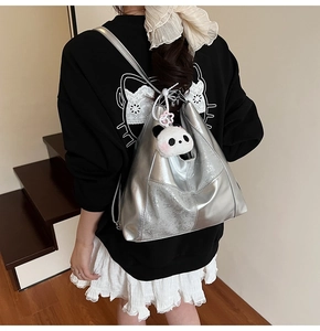 Detail of silver metallic tote bag with a panda plush charm shown on a staircase