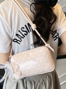 Pink polka dot baguette bag with lace bow and pearl chain shown on model
