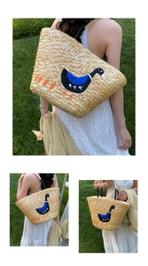 Detailed macro view of woven straw tote bag with Hola embroidery and black handles