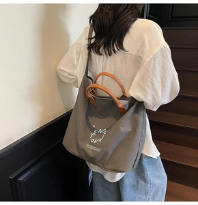 Detail view of grey canvas tote bag with brown straps worn by model on shoulder