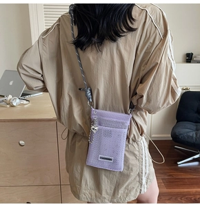 Detail of purple mesh crossbody phone bag with gray rope strap and silver heart charm