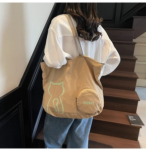 Close-up of khaki tote bag with cat print and round coin purse on a staircase