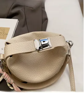 Close-up of minimalist cream leather handbag with silver lock and woven rope detail